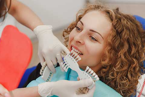 dentist selecting the correct shade of teeth whitening for a client